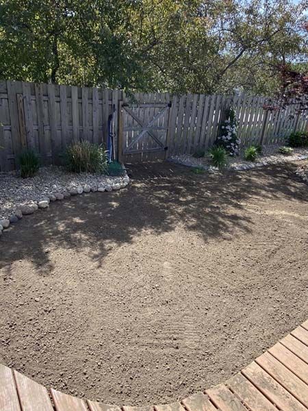 A wooden fence surrounds a circle of dirt in a backyard.