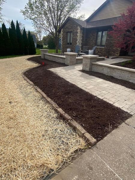 A house with a walkway and a brick wall in front of it.