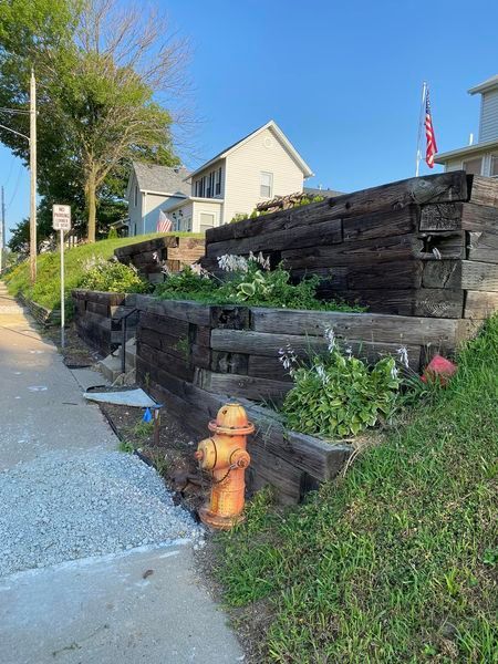 A fire hydrant is sitting on the side of the road next to a wooden wall.