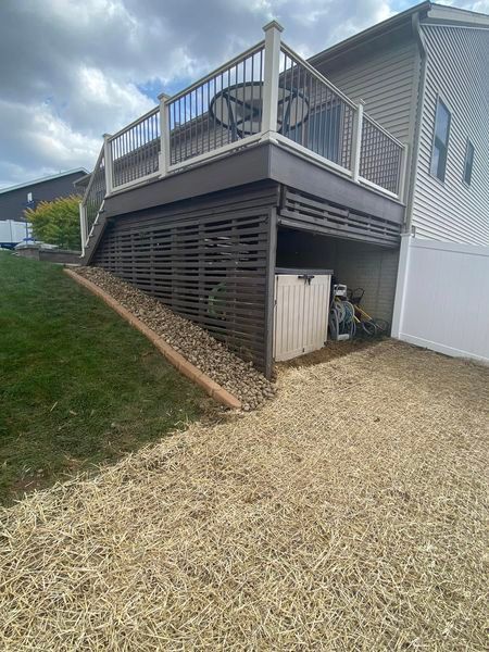 A deck with a table and chairs on it is on the side of a house.