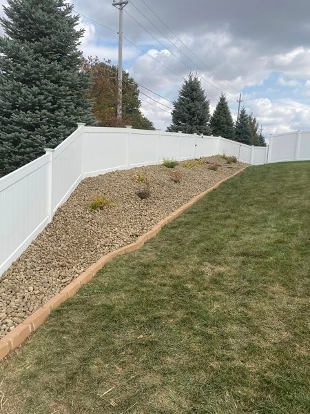 A white fence surrounds a lush green yard.
