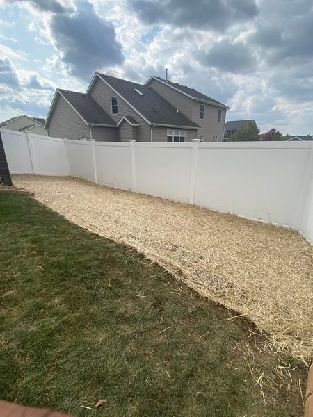 There is a white fence in the backyard of a house.