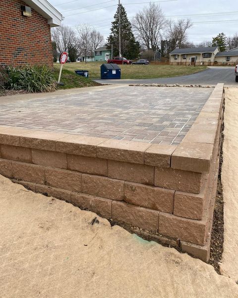 A brick wall is sitting next to a brick driveway.
