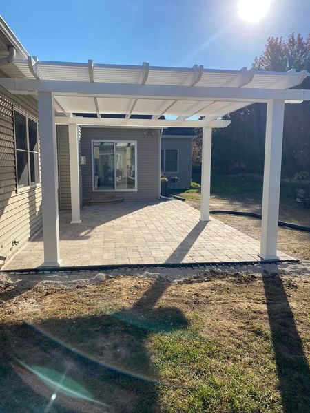 A white pergola is sitting in the backyard of a house.