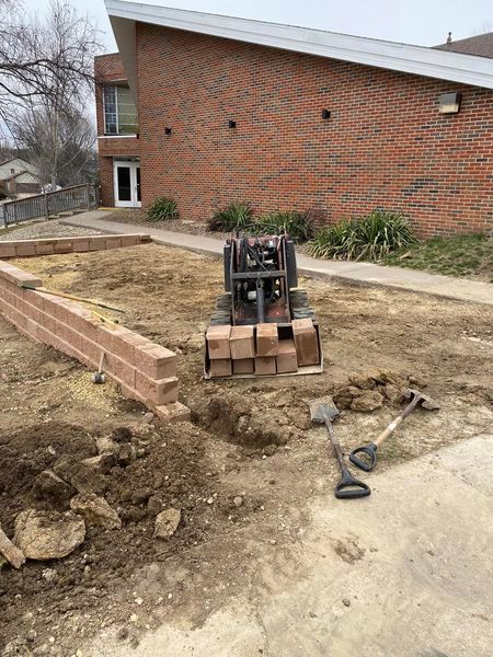 A brick wall is being built in front of a brick house.