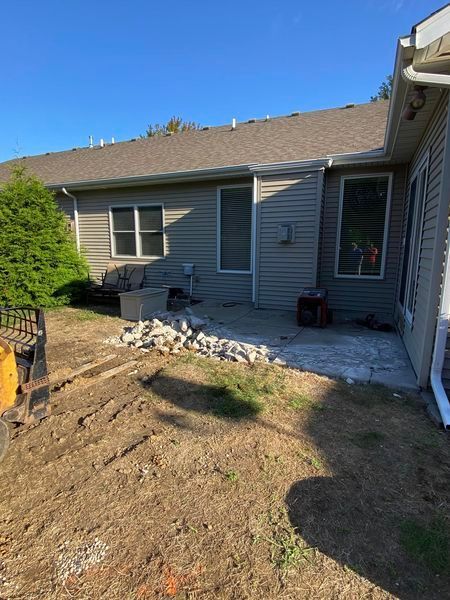 A house with a patio in front of it and a lot of dirt in front of it.