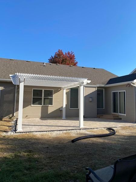 A house with a white pergola on the backyard