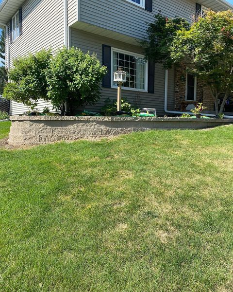A house with a birdhouse in front of it and a lush green lawn.