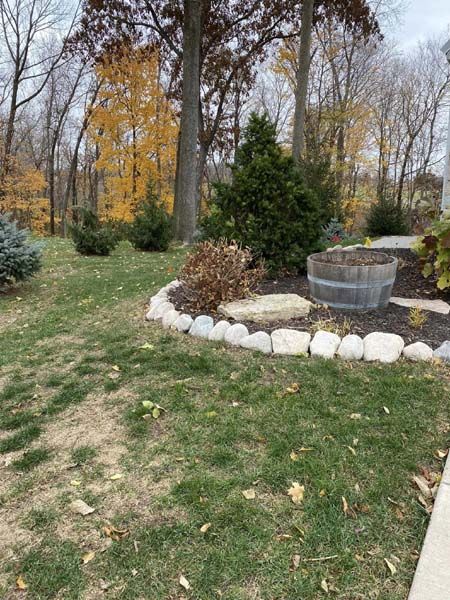 A lawn with a barrel in the middle of it and trees in the background.