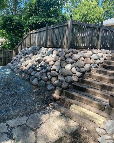 A wooden fence is surrounded by a pile of rocks and stairs.