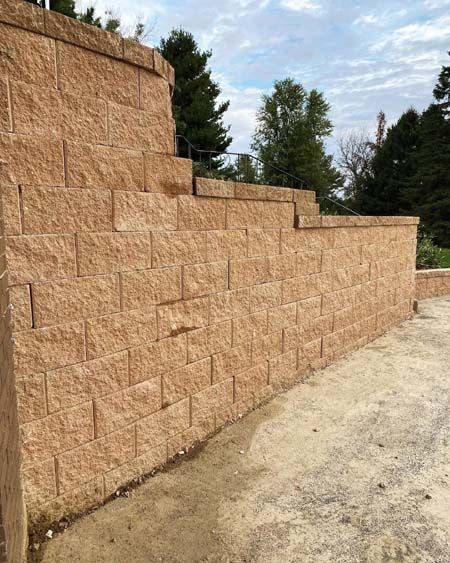 A large brick wall is being built next to a dirt road.