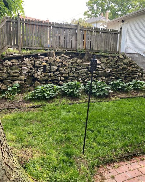 A backyard with a stone wall and a wooden fence.