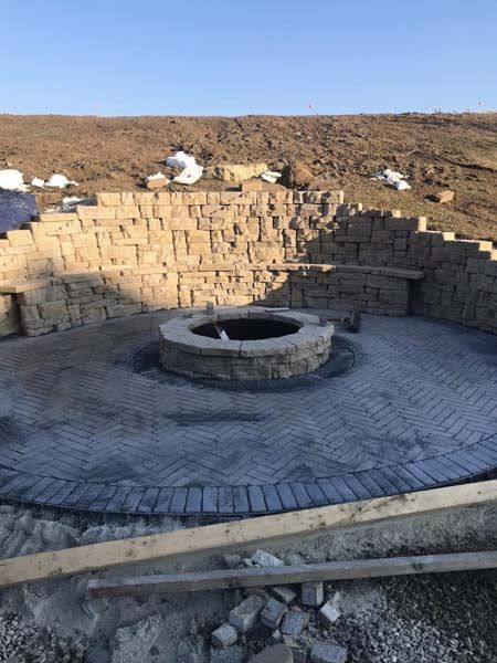 A fire pit is sitting in the middle of a brick patio.