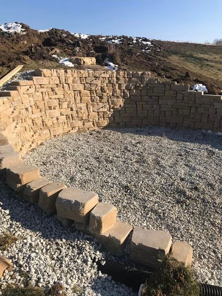 A brick wall is being built in the middle of a gravel area.