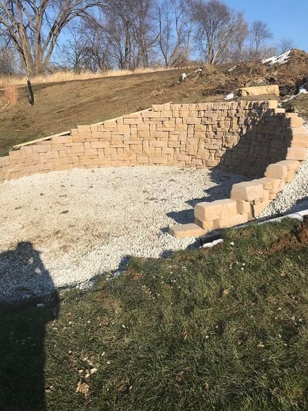 A stone wall is being built in the middle of a grassy field.