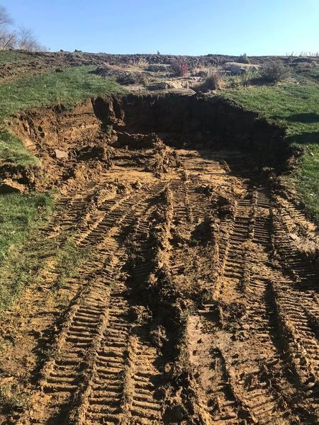 A muddy dirt road with tire tracks in the dirt.
