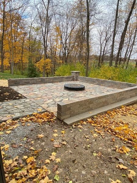 There is a fire pit in the middle of the patio surrounded by trees.