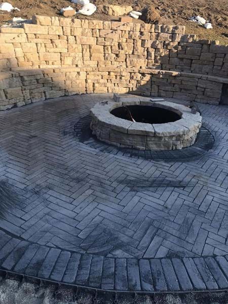 A fire pit is sitting in the middle of a brick patio.