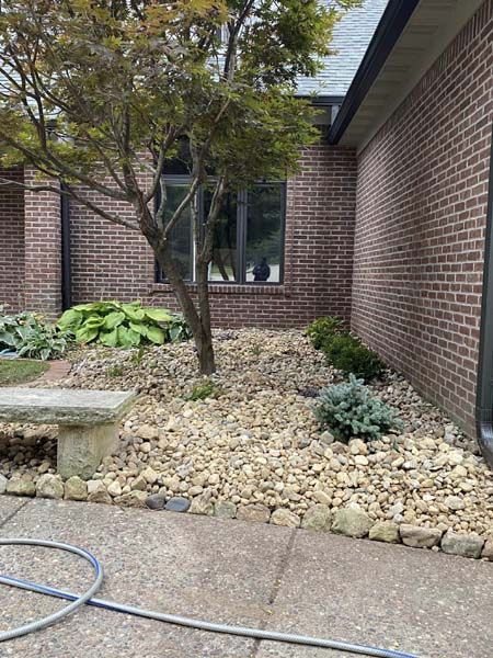A hose is sitting on the sidewalk in front of a brick building.