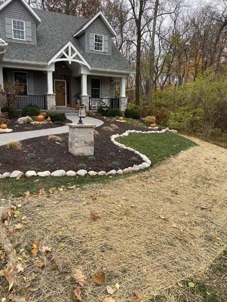 A house with a walkway leading to it and trees in the background.