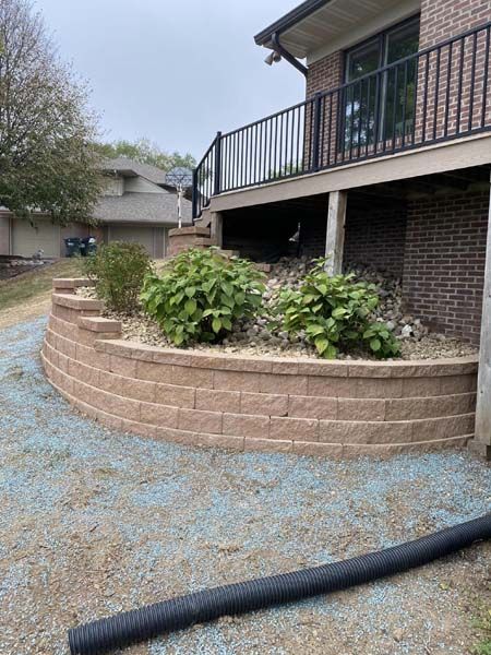 A brick wall in front of a house with a deck.