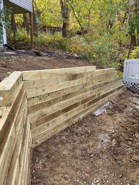 A wooden retaining wall is being built on top of a dirt hill.