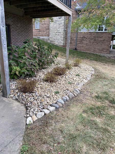 A garden with rocks and plants in front of a house.