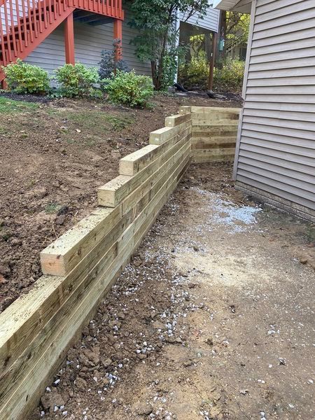 A wooden retaining wall is being built next to a house.