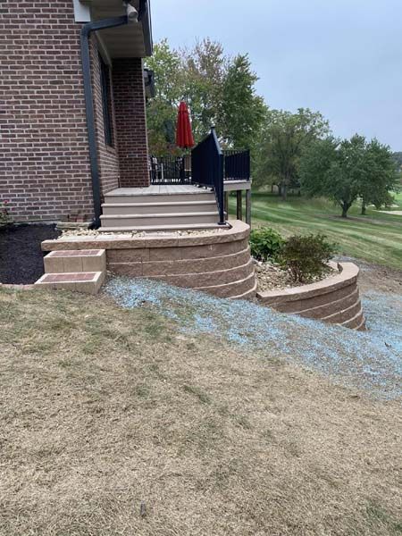 A brick house with stairs leading up to a patio with a red umbrella.