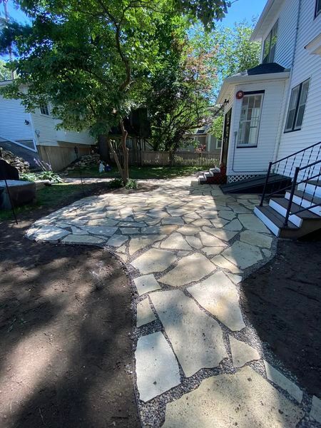 A stone walkway leading to a house with stairs.