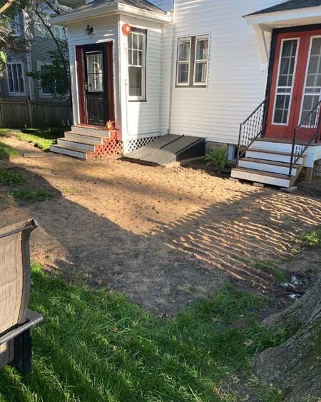 A white house with a red door and stairs in front of it.