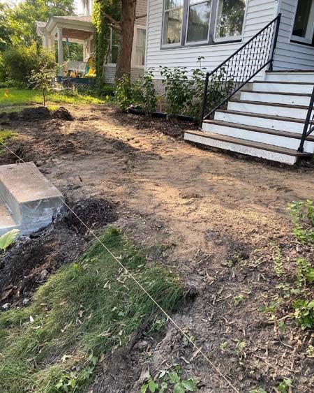A house with stairs and a dirt path in front of it.