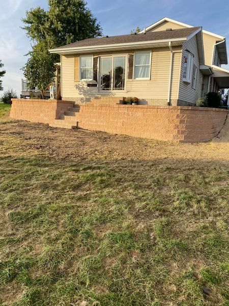 A house with a brick retaining wall in front of it.