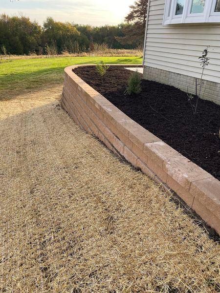 A brick wall surrounding a garden next to a house.