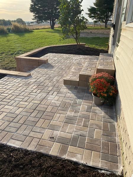 A brick patio with steps and a potted plant in front of a house.