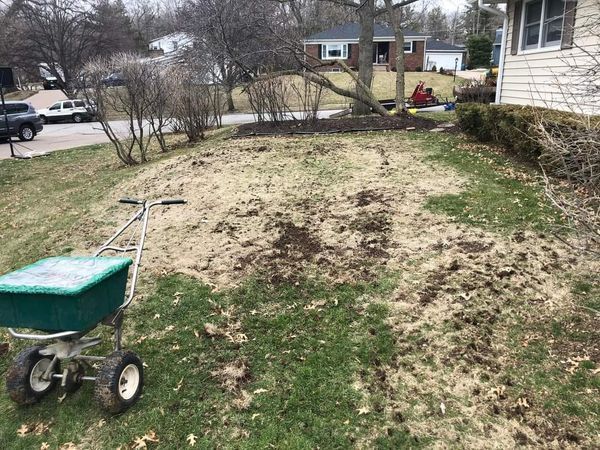 A wheelbarrow is sitting in the grass in front of a house.