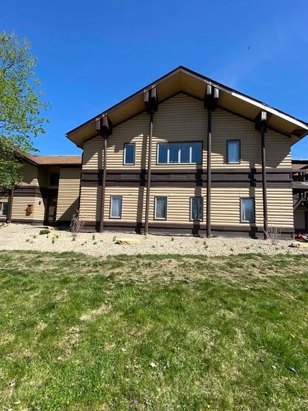 A large house with a lot of windows is sitting on top of a lush green field.