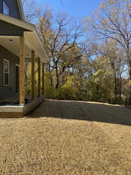 A house with a porch and a gravel driveway in front of it.