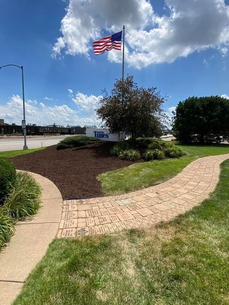A walkway leading to a building with a flag flying in the background.