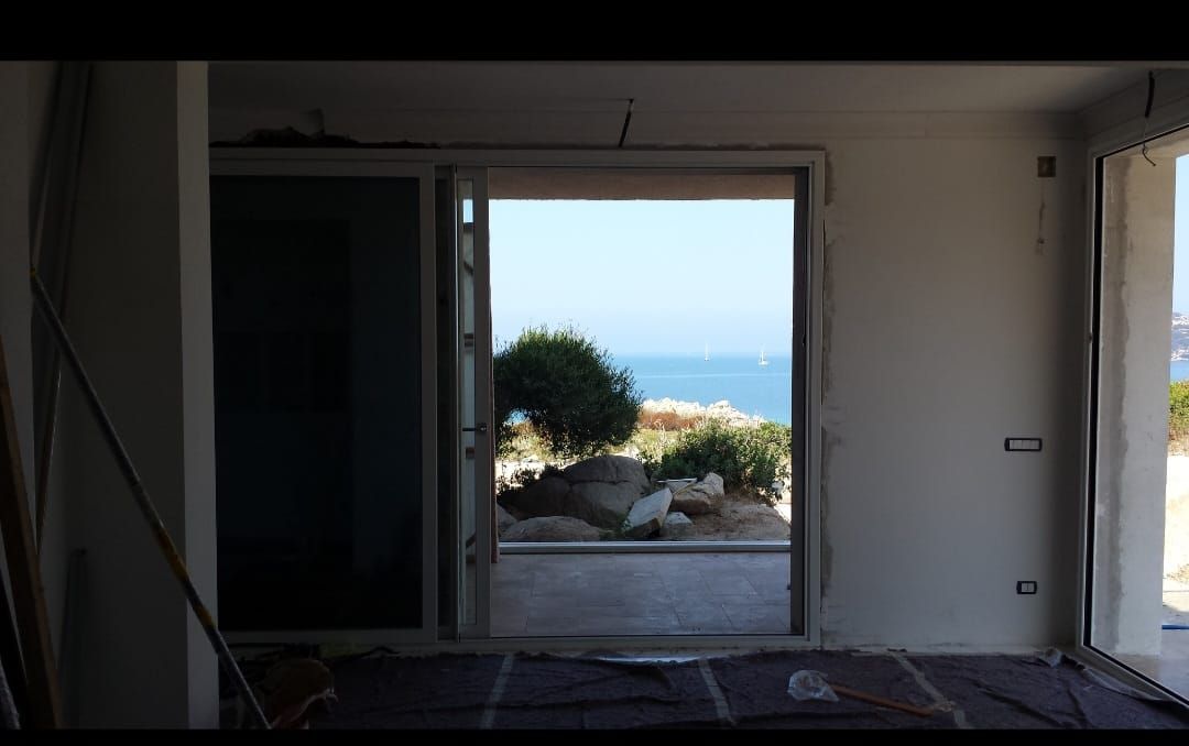 Una stanza con vista sull'oceano attraverso una porta scorrevole in vetro