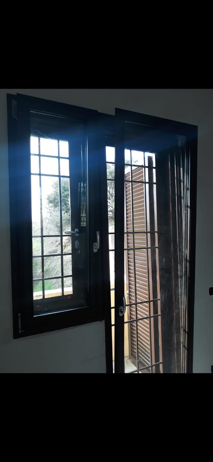 Una stanza con due finestre e una porta scorrevole in vetro.