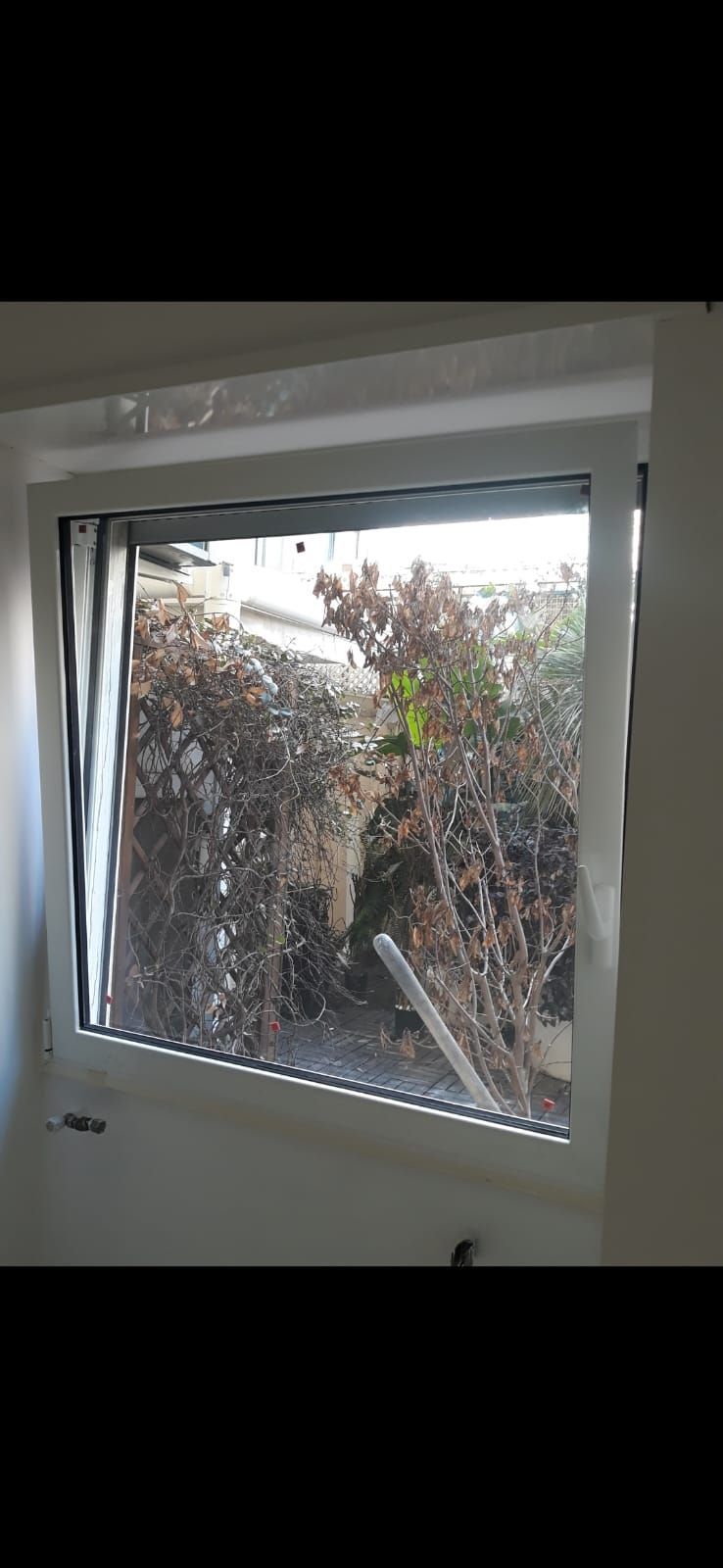 Una finestra in una stanza con una recinzione sullo sfondo.