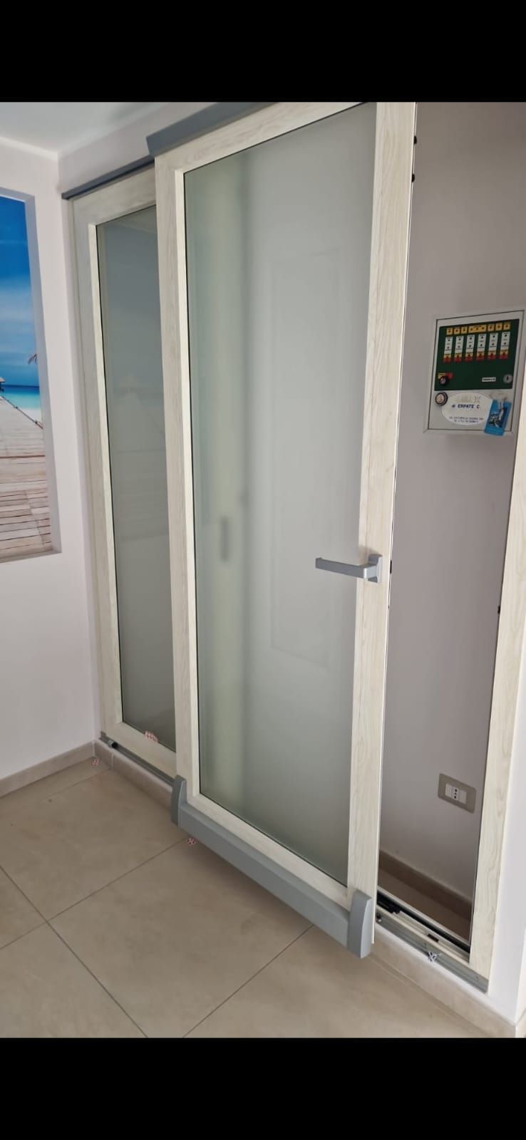 Una stanza con una porta scorrevole in vetro e un quadro sul muro.