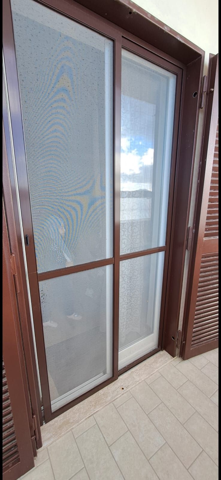 C'è una porta scorrevole in vetro con una zanzariera.