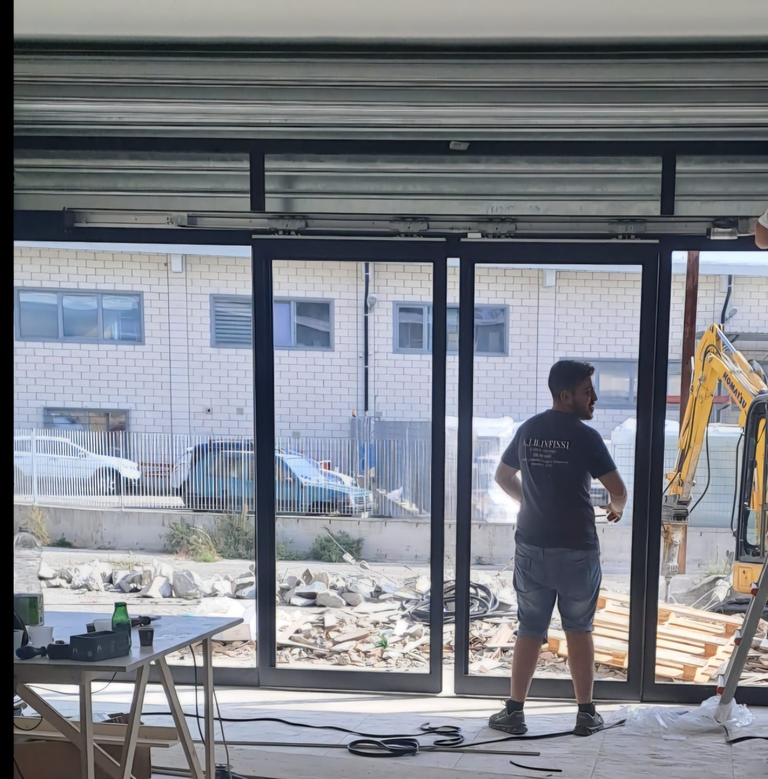 Un uomo con una camicia nera è in piedi davanti a una porta scorrevole in vetro.