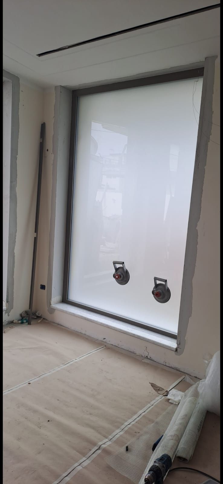 Una stanza con una grande finestra e un pavimento in legno.