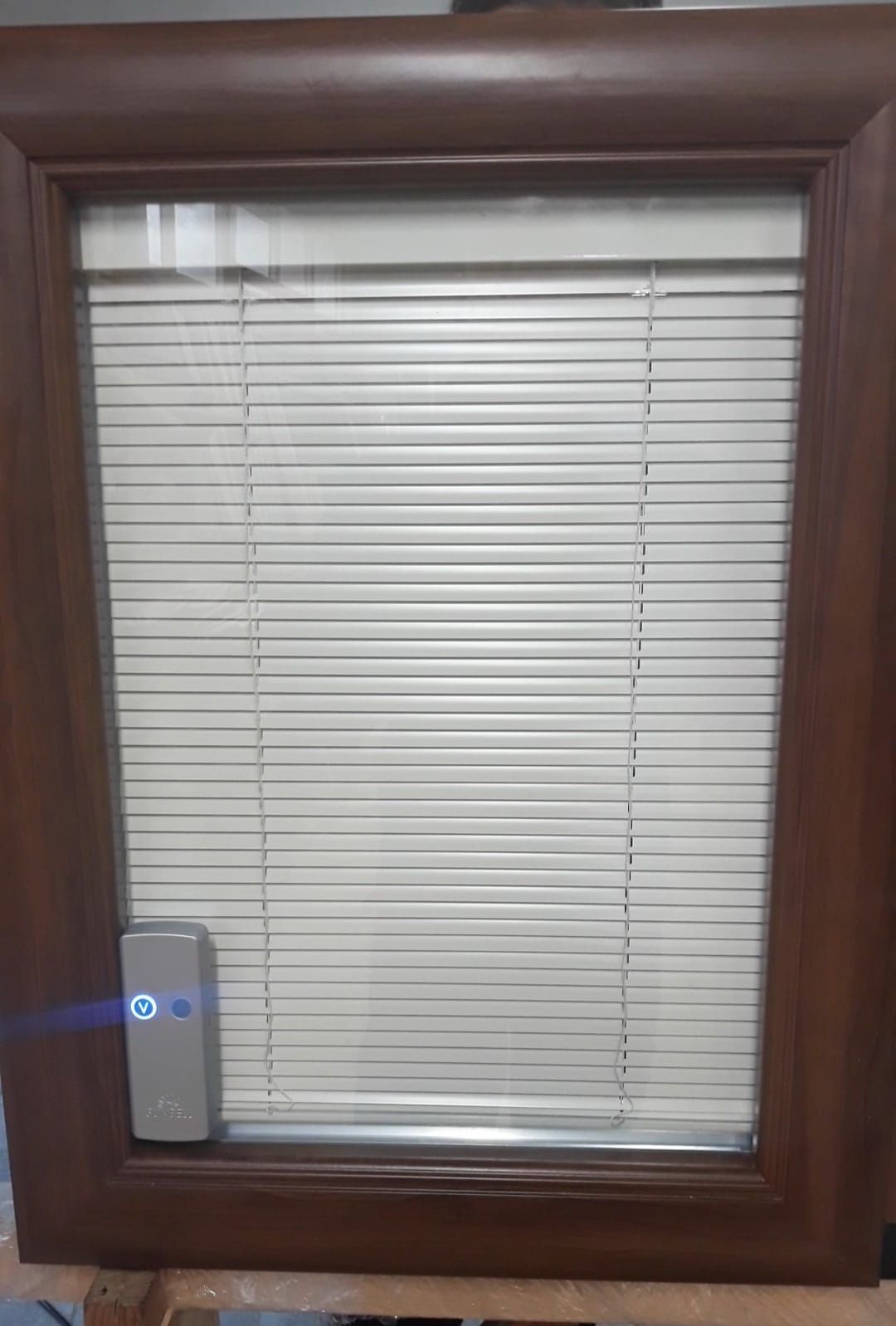 Una finestra con le persiane è appoggiata su un tavolo di legno.