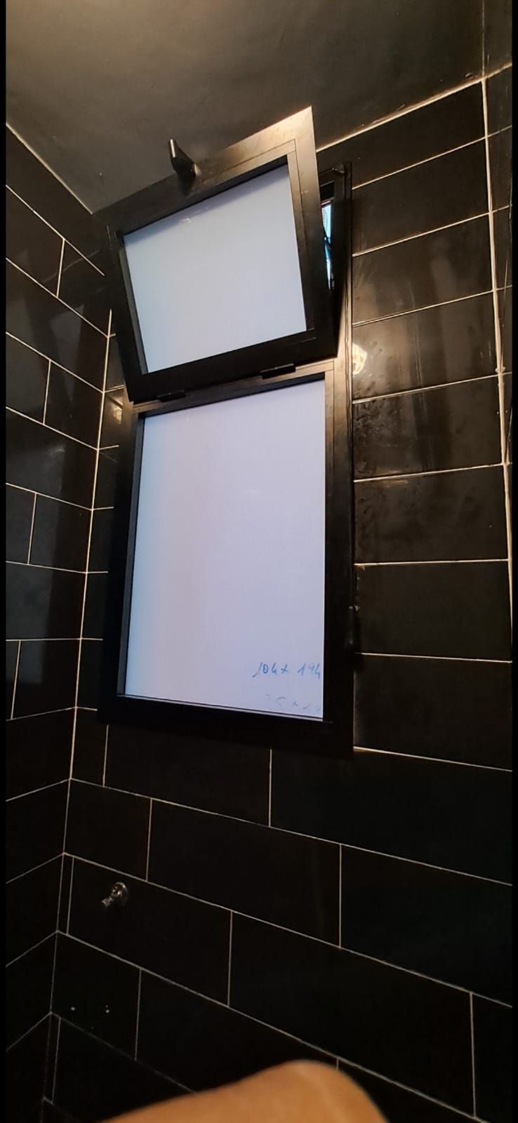 Un bagno con piastrelle nere e una finestra.