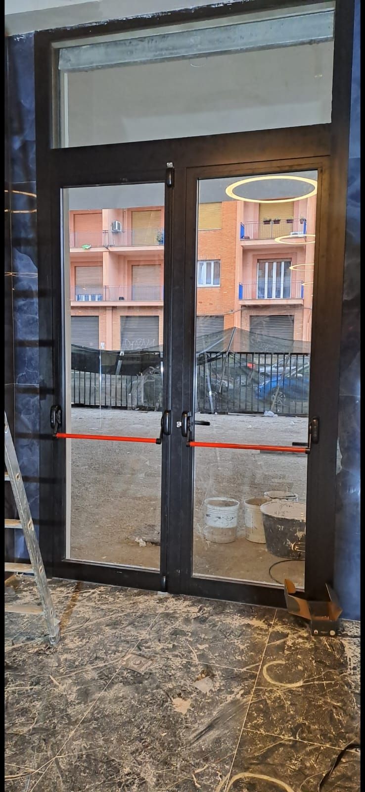 Una porta con una maniglia rossa è aperta in una stanza con una scala.