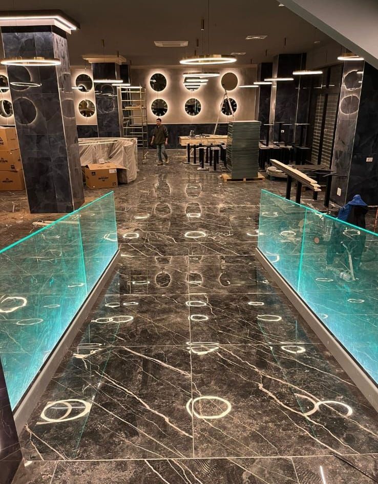 Un corridoio di un edificio con pavimento in marmo e ringhiera in vetro.